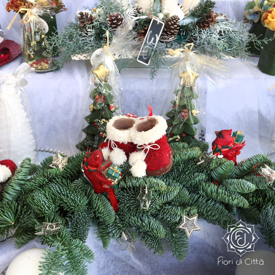 centrotavola natalizio con rami di pino e scarpette rosse e bianche in panno